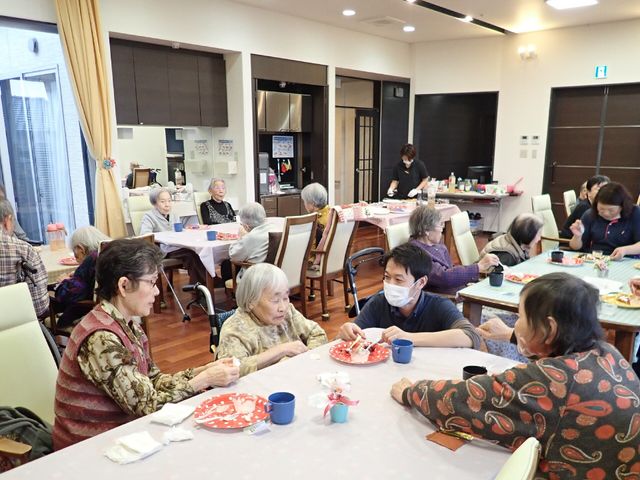 活気ある共有ダイニング レクリエーション 明るく広々とした食堂で、笑顔のあふれるコミュニケーションの場が設けられています。スタッフと利用者様が一緒に楽しい時間を過ごしています。