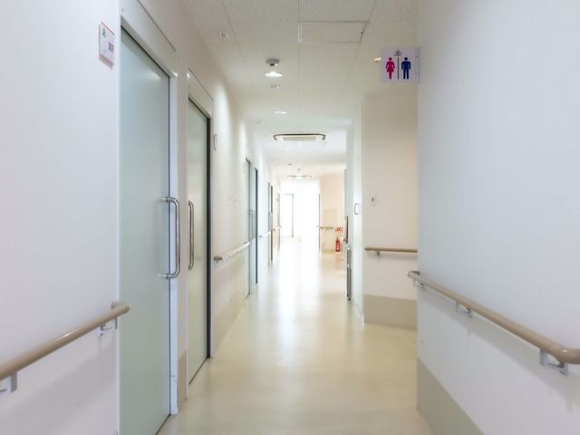 清潔な病院の廊下 廊下 広々とした廊下は明るく、手すりが整っているため、安全に歩行ができる設計です。壁は清潔感のある白色で、入り口は明確に示されています。
