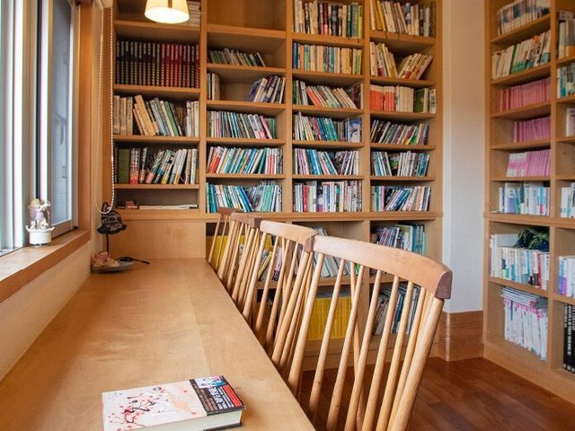 暖かい印象の読書スペース 図書室 広々とした本棚が並ぶ読書スペースです。窓際の明るい光が、心地よい読書時間を提供しています。