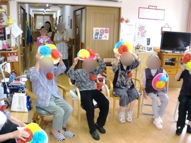 活動中のリビングの様子 レクリエーション 明るい雰囲気のリビングで、利用者が手作業で楽しそうに過ごしています。共有スペースでの活動は、日々の潤いにつながります。