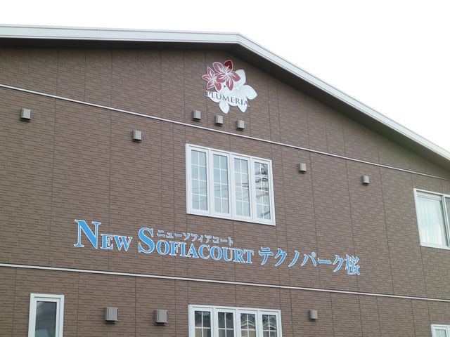 茶色の建物の外壁と看板 外観 清潔感のある外壁に名前が記された建物です。温かみのある色合いで、訪れた方を迎え入れます。