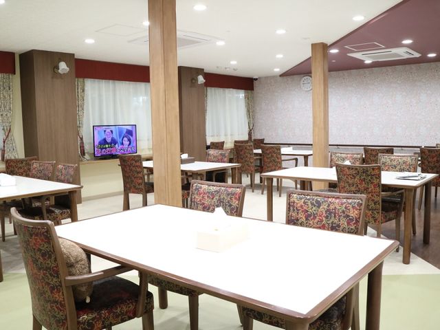 暖かみのある食堂 共有スペース ゆったりとした椅子が並ぶ食堂で、壁掛けテレビが娯楽を提供しています。センスの良い内装で、居心地の良い時間を過ごせる空間です。