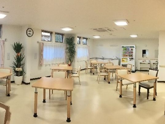 施設の写真 クリーム色の床や壁、木目丁のテーブルやイスが並んだ食堂