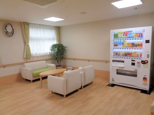 自動販売機が設置された談話スペースには白いソファが対面式に置かれ、観葉植物もある。