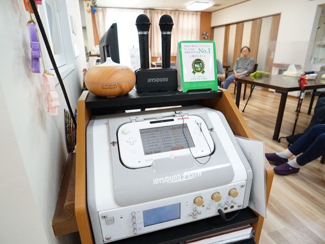 カラオケ設備とリラックスする人々 カラオケ機 居心地の良いスペースで楽しむカラオケ設備と検討者の表情が見てとれ、ゆったりとコミュニケーションを図れる環境が整っています。
