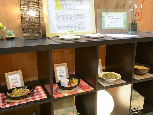 施設の写真 肉料理や魚料理がラックに展示されている。上にはチーズケーキとティラミスが置かれている