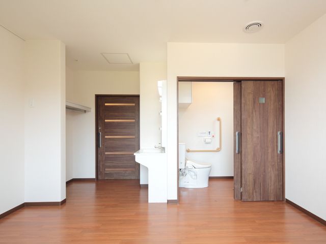 居室と洗面所の入口 居室 広々とした明るい居室があり、快適な生活空間が提供されています。洗面所へのアクセスも考慮されたバリアフリー設計です。