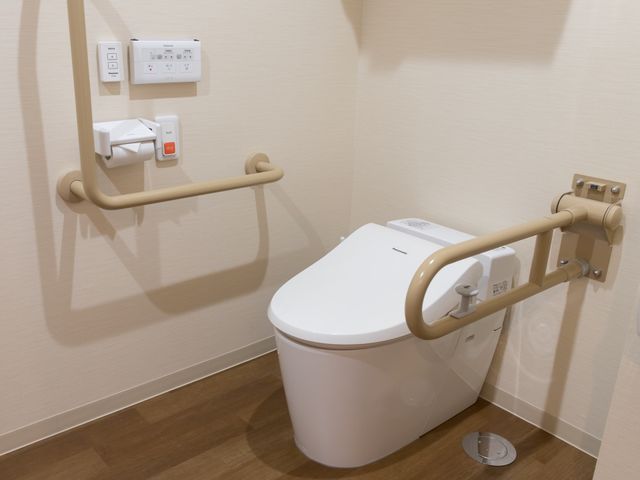 バリアフリートイレ設備 トイレ 手すり付きのモダンなトイレです。より安全で快適な利用をサポートし、働く環境としても配慮が行き届いています。