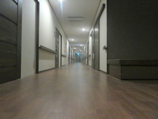 長い廊下 廊下   落ち着いた色合いの長い廊下で、奥まで見通しやすいです。両側に扉が並び、移動しやすい印象です。