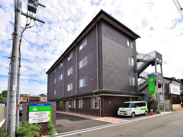 外観と緑の案内看板 外観 清潔感があり落ち着いた色合いの建物です。前方には訪問者を迎える案内看板が設置されています。