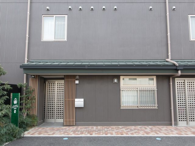 モダンな建物のエントランス 外観 清潔感あふれる落ち着いた色合いの入口は、来訪者を温かく迎えてくれます。閑静な雰囲気の中で、訪れる方々の心地良い一日のスタートをお手伝いします。