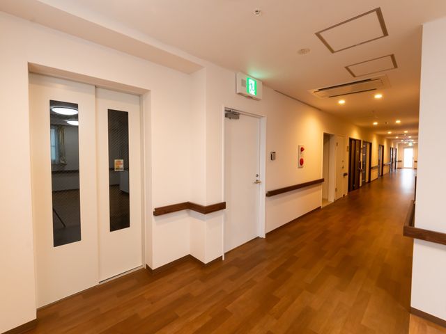清潔な廊下の風景 通路 床がきれいに保たれた廊下は、歩きやすく、明るい印象を与えます。壁には手すりが設けられており、歩行に安心感があります。