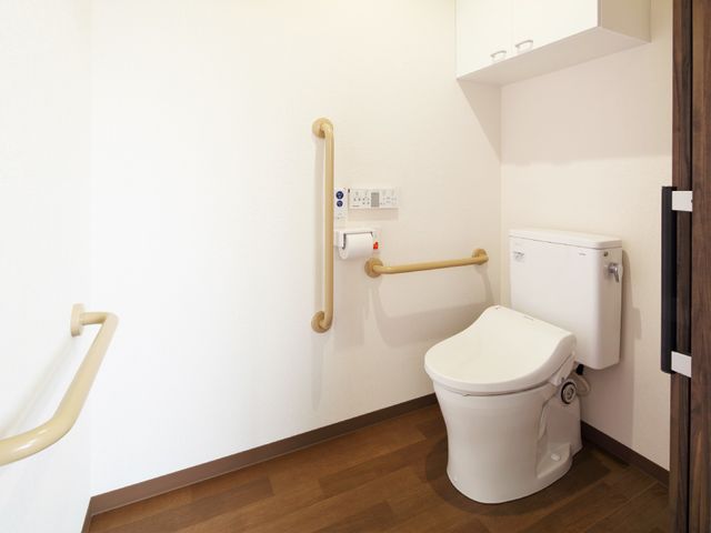バリアフリー設計のトイレ トイレ 手すり付きの安全を考慮した清潔なトイレです。使用者の快適さと自立を支援する工夫が施されています。