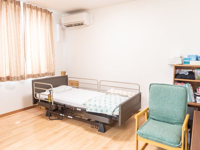 快適な居室の一角 居室 すっきりとした空間の居室で、快適にお過ごしいただけます。日差しを採り入れる窓と、機能性を備えたベッドが配されています。