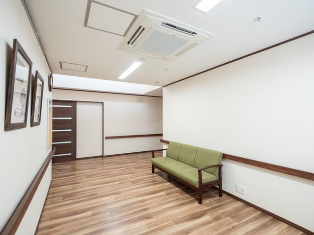 広々とした清潔な廊下 通路 落ち着いた色合いの廊下にはベンチも設置され、ゆったりとした時間を過ごせる空間です。フラットで広々としたデザインは、快適な動線を確保しています。