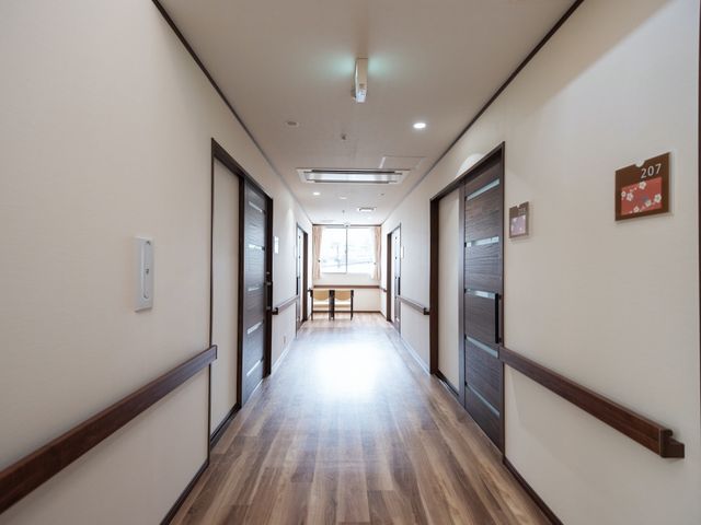 清潔感のある廊下 通路 床から天井まで木目調で統一された廊下は、心地よい雰囲気を醸し出しており、そこを通ることで安らぎを感じられる空間です。