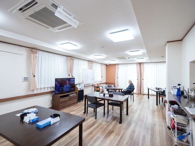 快適な居室内空間 食堂 広々とした居室で、一人の方がテーブル席でくつろがれています。職員とのコミュニケーションも充実しそうな温かい雰囲気です。