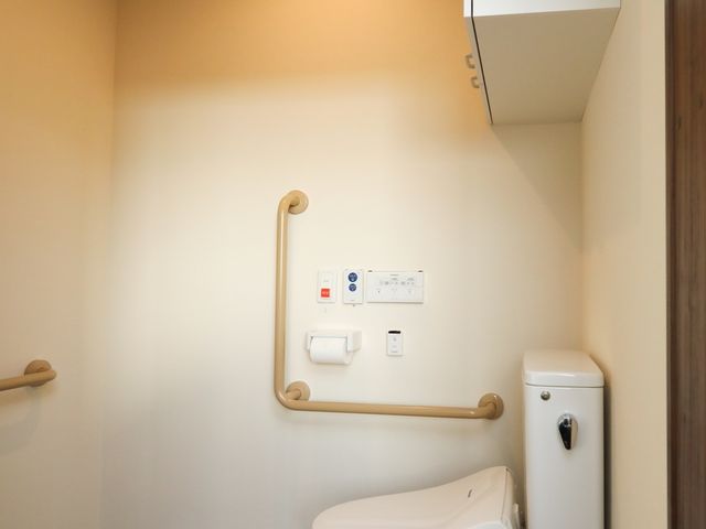 清潔なトイレ空間 トイレ 手すり付きでバリアフリー設計のトイレです。落ち着いた色合いで、ゆったりとした使用感を提供しております。