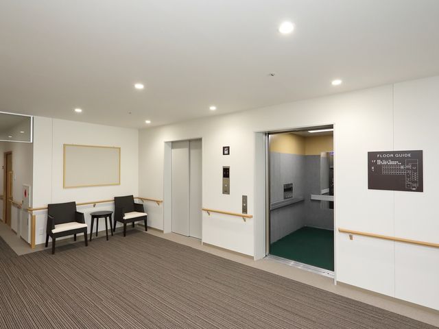 清潔感のある廊下の一角 エレベーター 手すりが設けられた廊下は、清潔で広々としており、快適な移動空間を提供しています。利用者の方々の安全を考慮した設計です。