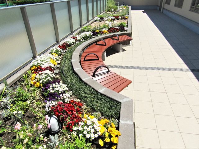 花壇とベンチの中庭 ルーフテラス 色とりどりの花が植えられた中庭には、ゆったりくつろげるベンチがあります。外の空気を感じながらのひとときをお過ごしいただけます。