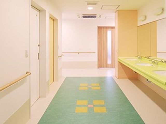 手すり付きの明るい廊下 廊下 手すりが整備された廊下は、安全に配慮された設計となっており、安心して歩行ができる環境です。壁面の色合いやフローリングも落ち着いた雰囲気を醸し出しています。