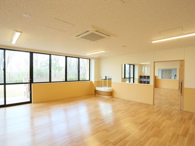 広々とした機能訓練室 共有スペース 大きな窓で自然光が差し込む明るいスペースです。床は滑りにくい素材で、安全性に配慮されています。