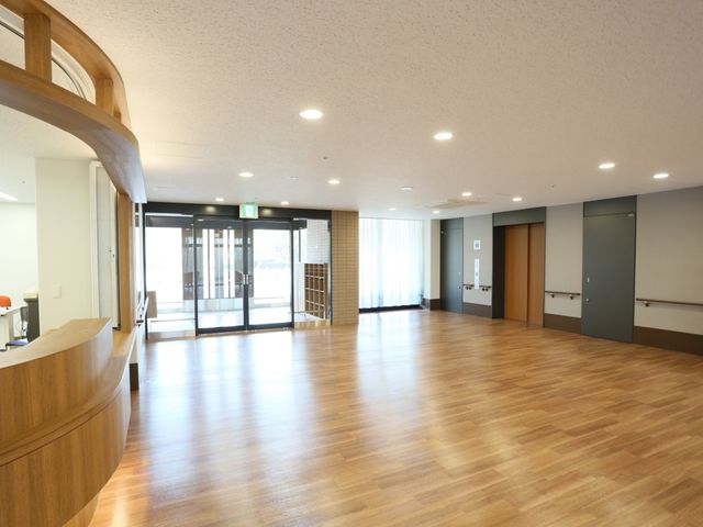 明るい広々とした共有スペース 玄関 開放的なラウンジでは、木のぬくもりを感じながら、ゆったりとした時間を過ごすことができます。バリアフリー設計で安心してお過ごしいただけます。