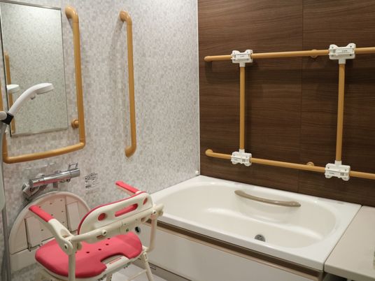複数の手すりが設置されている個浴である。洗い場には、背もたれとひじ掛けの付いたシャワーチェアが用意されている。