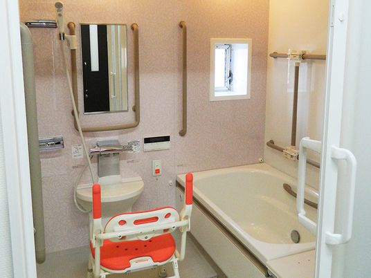 一人用の浴槽が設置された浴室。シャワーやシャワーチェアもあり、手すりが壁についている。