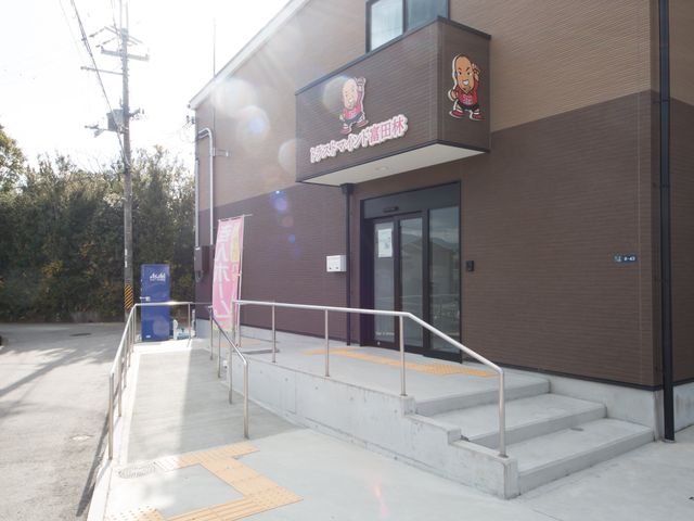 施設の入口と看板 外観 清潔感のあるエントランスが迎えてくれる施設です。明るくモダンなデザインで、来訪される方々をお迎えします。