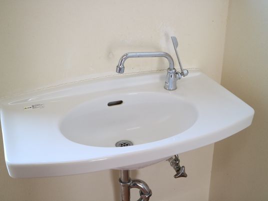 施設の写真 真っ白でシンプルな洗面台が設置されている。レバーを回して簡単に操作することができる。足元にスペースが確保されている。