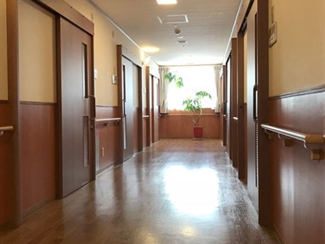 広々した明るい廊下 廊下 温かみのある木目調の廊下が、心地よい移動空間を生み出しています。壁には手すりが設置され、安全に配慮されています。