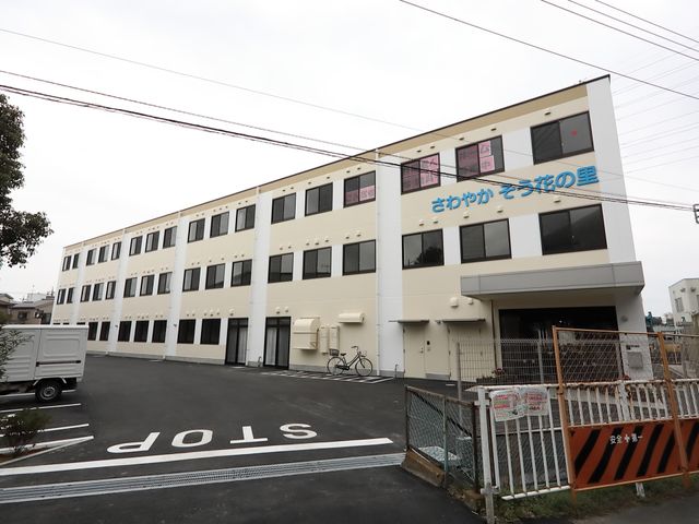 清潔感ある外観の建物 駐車場 落ち着いた色合いの外観は、周囲の環境に調和しており、訪れる人々を温かく迎え入れます。車椅子でも容易にアクセス可能な入口を設け、安全性にも配慮しています。