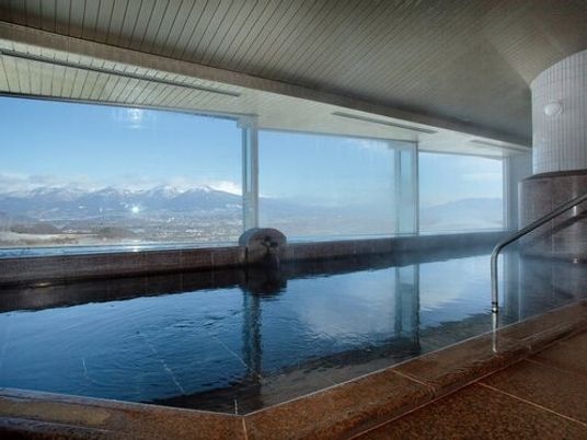 施設の写真 山脈を眺めながら入浴できる広い浴室。長方形の浴槽が窓際に設置され、出入り口には手すりもある。