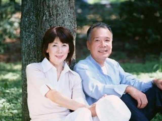 笑顔の高齢カップル中庭にて 広々とした中庭では、青々とした木々の下で心地よいひとときを過ごせます。利用者の笑顔が印象的で、ゆったりとした時間が流れる空間です。