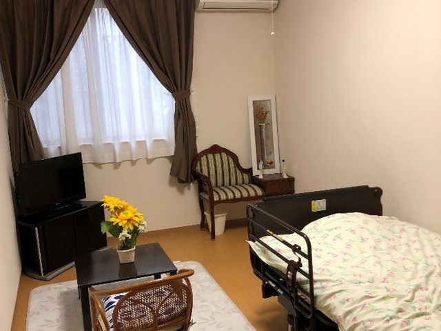 居心地の良い居室 居室 ゆったりとした時間を過ごせる居室です。温かみのある家具と花が、安らぎを提供しています。