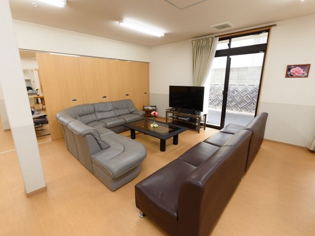 居室の明るいリビング リビング ゆったりとしたソファが配置された居室で、共有のリラックスタイムをご提供しています。窓からは自然光が差し込み、落ち着いた雰囲気の中でお過ごしいただけます。