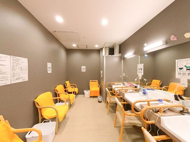 機能訓練の風景 脱衣所 黄色い椅子が並ぶ落ち着いた雰囲気のスペースです。様々なトレーニング機器が備え付けられ、日々のリハビリに活用いただけます。