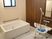 洗い場側の壁が木目調になっている、落ち着いた雰囲気の個浴室である。白色の浴槽とシャワーチェアが備わっている。