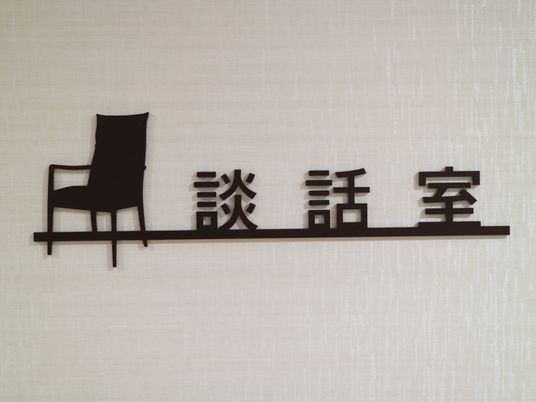 壁に、談話室の看板が設置されている。文字の横に椅子の形の飾りが付いており、下部に線が引かれたデザインである。