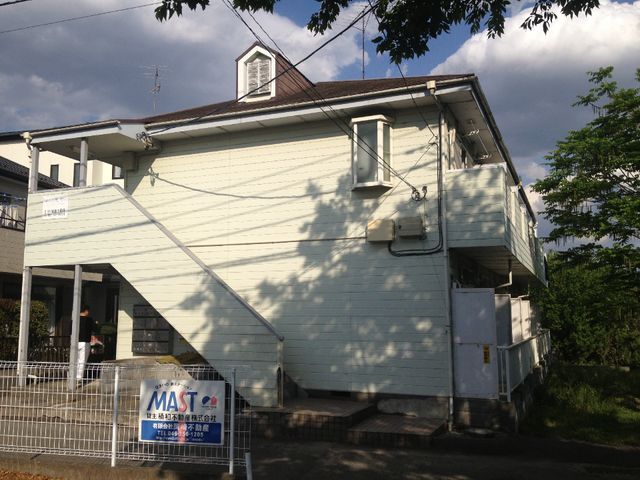 白い壁の建物と青空 外観 心地よい陽光が降り注ぐ、家庭的な雰囲気のある外観です。築年数の感じられる建物が、長年の安心感を提供しています。