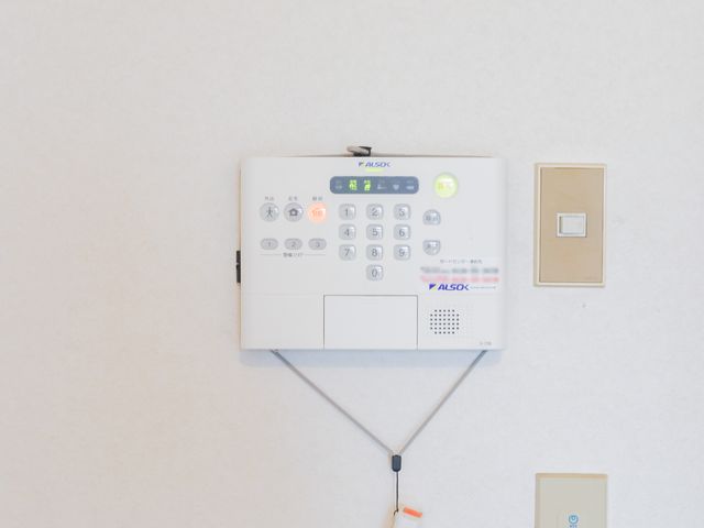 白い壁に取り付けられたナースコール 居室 どんな時でも迅速に対応できる安心のナースコールシステムが整っています。あなたの手による、心強いサポートを期待しています。