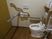 トイレの便器の前には灰色の安全バーを設置している。入居者様はトイレを使用する際に倒れ込むことを防止できる。