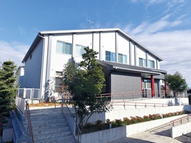 建物の外観 外観   白い外壁の2階建てで、明るく清潔感のある雰囲気です。階段やスロープが見え、出入りしやすいつくりに見えます。