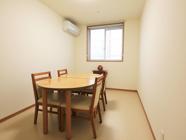 シンプルな居室の角部分 談話室 円形のテーブルを囲む居室は、静かで落ち着いた雰囲気です。個人の時間を大切にしながら安らぎを得られる空間となっています。