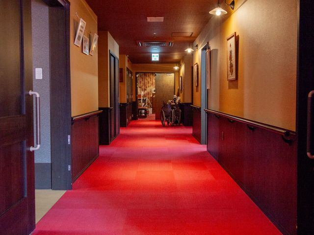 温かみのある廊下 廊下 廊下の先に人影が見え、安心感と共に働く環境が伺えます。壁には額装された絵があります。