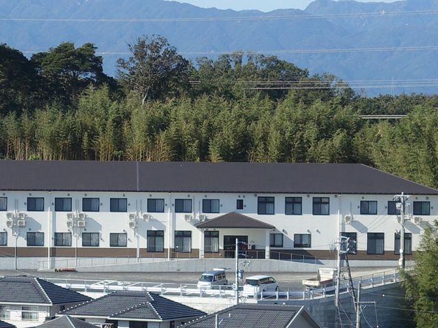 山々と緑に囲まれた建物 外観 広々とした駐車場がある、自然豊かな環境に建つ施設です。清々しい空気の中でゆったりとした時間を過ごしていただけます。