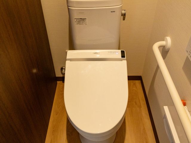 安全に配慮したトイレ トイレ 手すりが付いたトイレで、安全に利用できる配慮がされています。温かみのある木の床が特徴です。