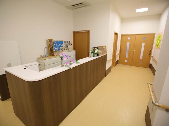 明るい廊下と受付カウンター 事務室 清潔感あふれる受付エリアでは、訪れるみなさまを暖かくお迎えします。毎日の業務で快適な対応が期待できる設計です。