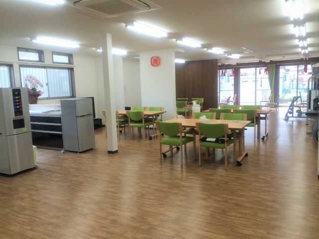 広々とした食堂空間 デイサービス 木目調の床と緑色の椅子が心地よさを演出する明るい食堂です。家庭的な雰囲気の中でお仕事ができ、利用者様の笑顔に接することができます。